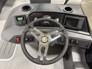 Helm dashboard featuring navigation screen, control switches, and steering wheel for optimal boat op.