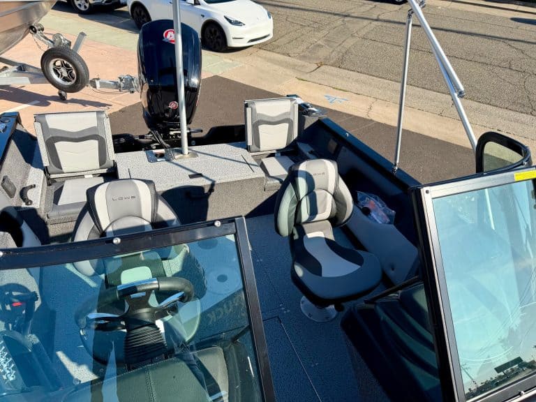 Boat with seating and steering wheel, ready for sale or launch at a marine dealership.