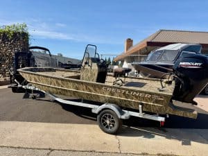 Boat on trailer with Mercury outboard motor at a marina.