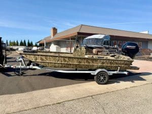 Opti-friendly boat with camouflage design and Mercury outboard motor.