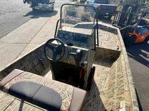 Opti boat with camouflage pattern, steering wheel, and dashboard for fishing and recreation.