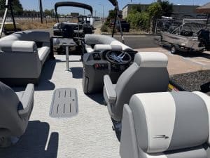 Pontoon boat cockpit with steering wheel, control panel, and comfortable seating for leisure boating.