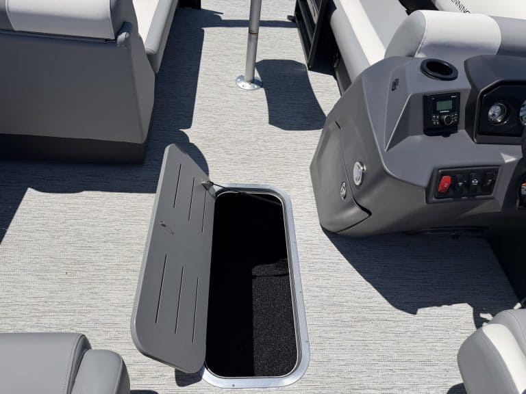 Boat dashboard with open storage compartment and electronic controls.