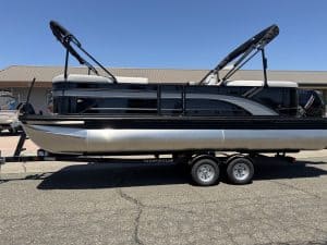 Luxury pontoon boat with dual Bimini tops, sleek black and silver design, on a trailer ready for boa.