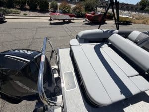 Aluminum boat with cushioned seating and outboard motor on trailer for sale or transport.