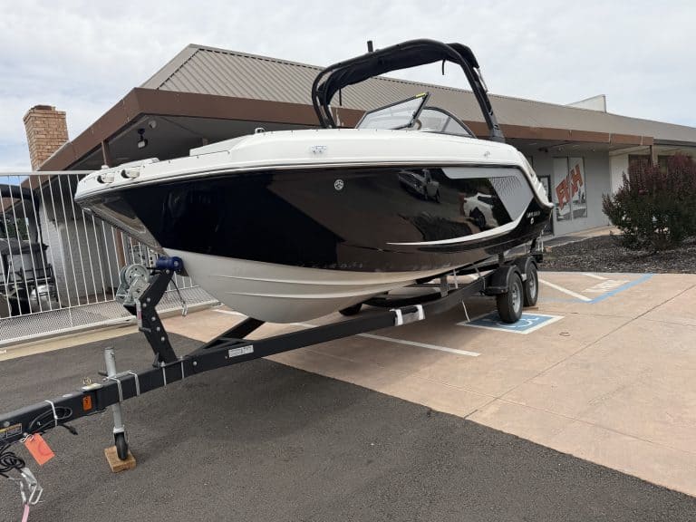 Boat with black and white hull on trailer at marina.