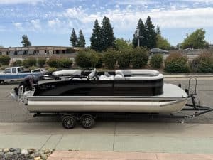Pontoon boat with black and white exterior on trailer, ready for water, ideal for leisure and fishin.