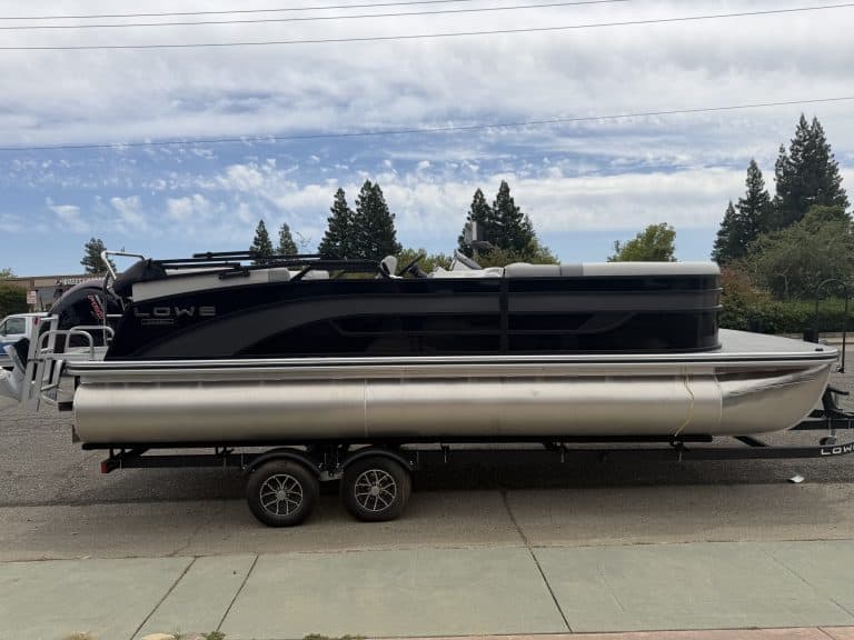 Pontoon boat with black and silver design on trailer, ready for water adventures. Perfect for leisur.