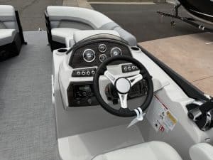 Helm station featuring steering wheel, gauges, and controls on a modern boat.