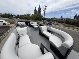 Boat with modern white and gray seating, ready for water, parked outdoors on a trailer.