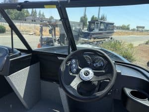 Boat interior with steering wheel and dashboard view from inside.