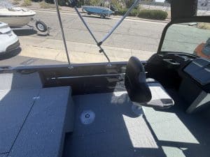 Boat interior with captain's seat and dashboard, outdoor scene in background.
