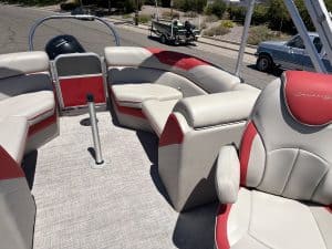 Pontoon boat interior with white and red cushioned seating and steering console.
