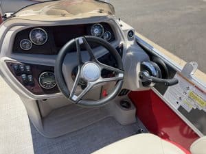 Close-up of boat console with steering wheel and instrument gauges.