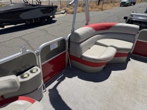 Pontoon boat seating area with red and white cushions and cup holders.