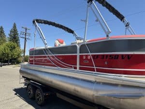 Red and white South Bay LE pontoon boat with Mercury 150HP engine on trailer.