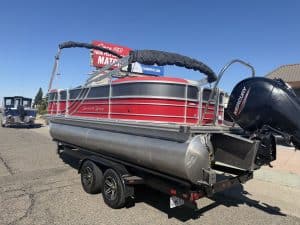 Red and silver pontoon boat with Mercury outboard motor on trailer.