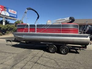 Pontoon boat with Mercury 150HP engine on trailer at dealership.