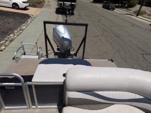 Boat with outboard motor on trailer parked on street.