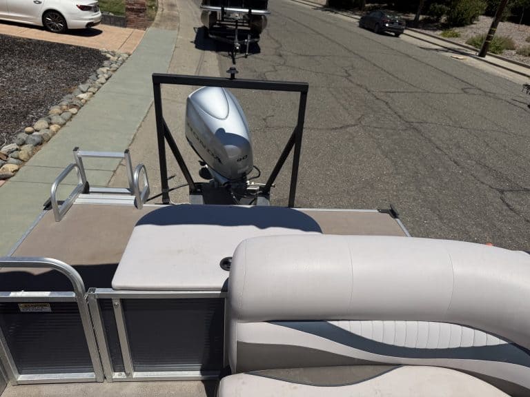 Boat with outboard motor on trailer parked on street.