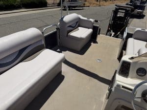 Pontoon boat with white cushioned seats and steering console.
