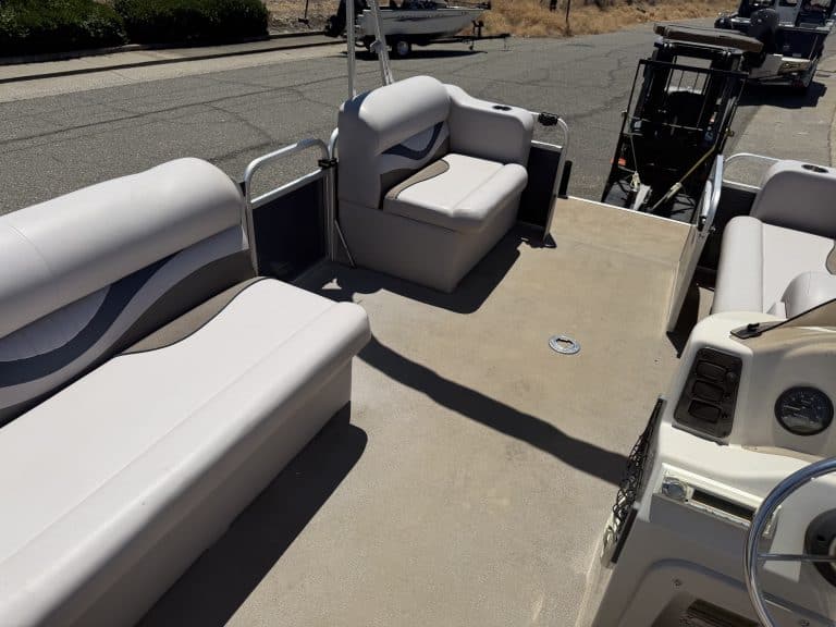 Pontoon boat with white cushioned seats and steering console.
