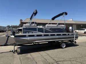 Pontoon boat on trailer with canopy and outboard motor.