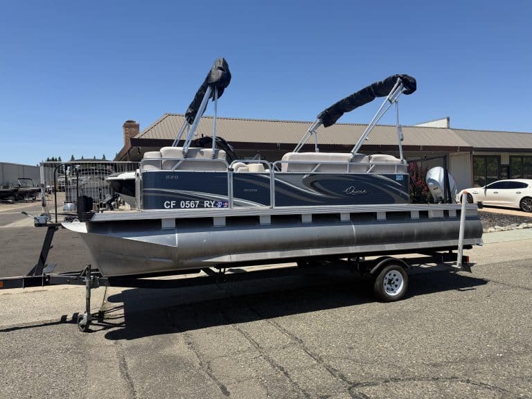 Pontoon boat on trailer with canopy and outboard motor.