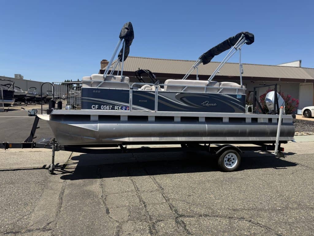 Pontoon boat on trailer at ASFB Marine with clear blue sky.