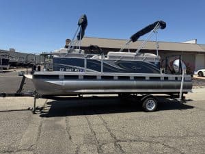 Pontoon boat on trailer at ASFB Marine with clear blue sky.