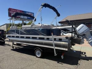 Lowe pontoon boat with Honda outboard motor on trailer at dealership.
