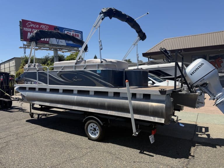Lowe pontoon boat with Honda outboard motor on trailer at dealership.