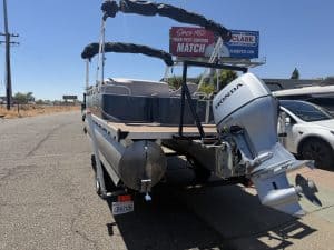 Pontoon boat with Honda outboard motor parked outdoors.