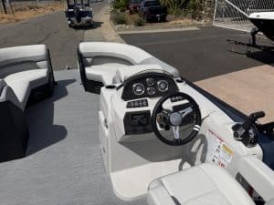 View of boat interior with steering wheel and seating area.