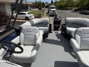 Luxury boat interior with white cushioned seats and steering wheel.