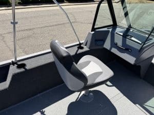 Boat cockpit with steering console and captain's seat in bright sunlight.