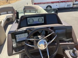Close-up of boat dashboard with steering wheel and digital displays.