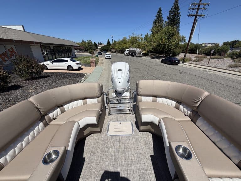 Bennington 25FT Q pontoon boat with beige seating and outboard motor.