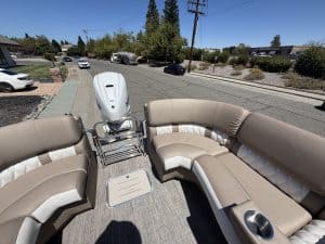 Bennington 25FT Q pontoon boat with beige seating and outboard motor.