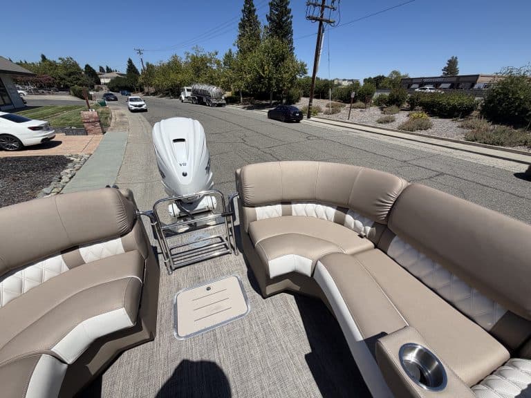 Bennington 25FT Q pontoon boat with beige seating and outboard motor.