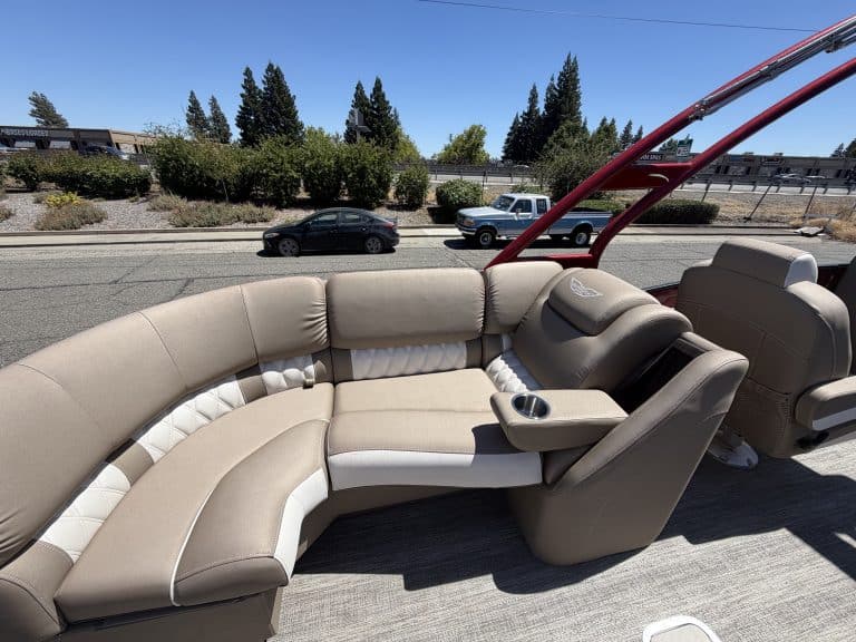 Luxury pontoon boat interior with beige seating and steering console.