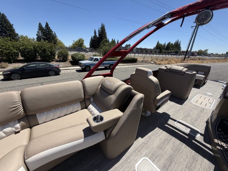 Luxury pontoon boat interior with beige seating and cup holders.