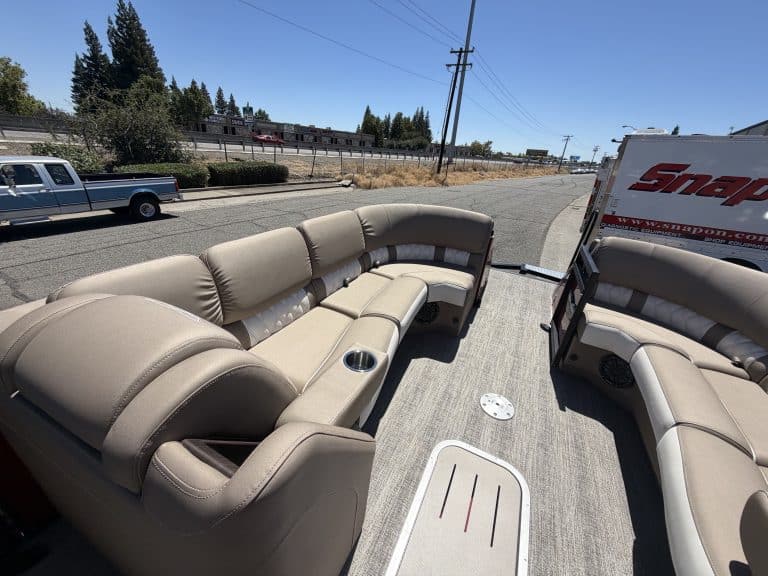 Luxury pontoon boat interior with beige seating and cup holders.