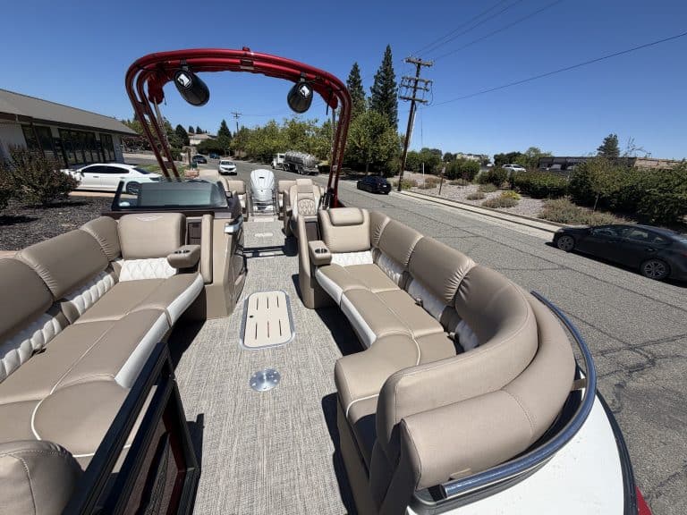 Bennington 25FT Q pontoon boat with beige seating and red canopy.