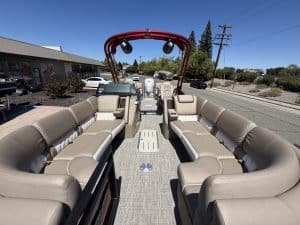 Bennington 25FT Q pontoon boat with beige seating and red canopy.