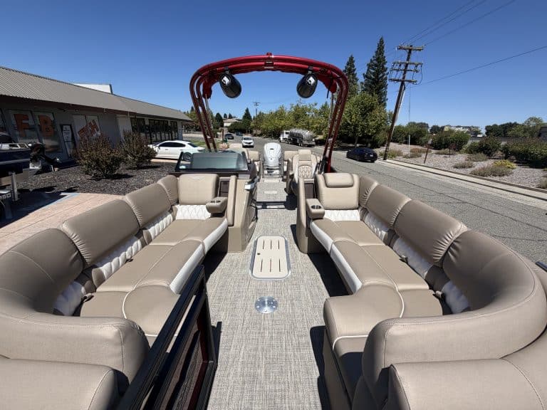 Bennington 25FT Q pontoon boat with beige seating and red canopy.