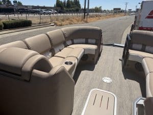 Luxury pontoon boat interior with beige seating and cup holders.