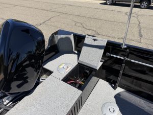 Close-up of boat interior with storage and motor in a parking lot.