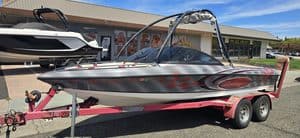 Speedboat on pink trailer with a boat dealership in background.