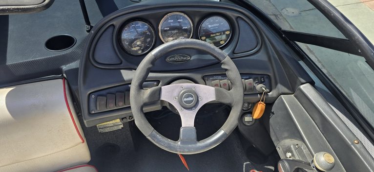 Boat steering console with gauges and steering wheel for marine navigation.